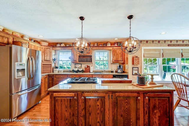 kitchen with stainless steel appliances, an inviting chandelier, plenty of natural light, and a kitchen island