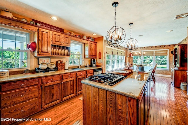 kitchen featuring light wood-type flooring, sink, an inviting chandelier, a kitchen island, and hanging light fixtures