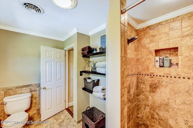 bathroom with tiled shower, toilet, tile walls, and ornamental molding