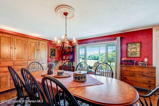 dining room featuring wood-type flooring, a textured ceiling, and an inviting chandelier