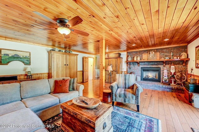 living room with hardwood / wood-style floors, wooden walls, a brick fireplace, ceiling fan, and wood ceiling