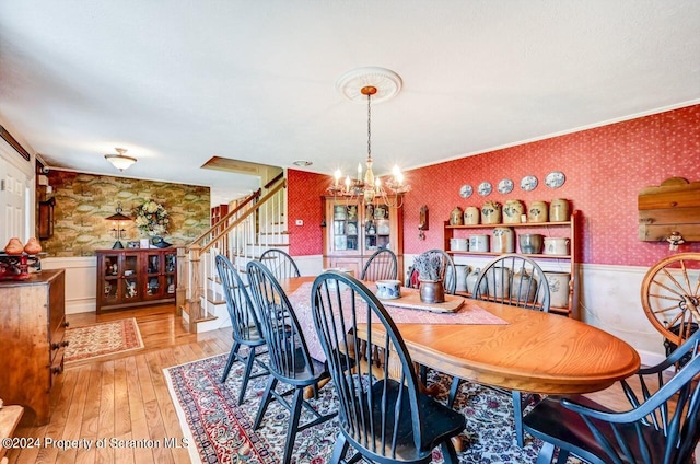 dining room featuring light hardwood / wood-style floors, ornamental molding, and a chandelier