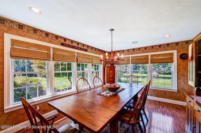 dining room with dark hardwood / wood-style flooring, a textured ceiling, and an inviting chandelier