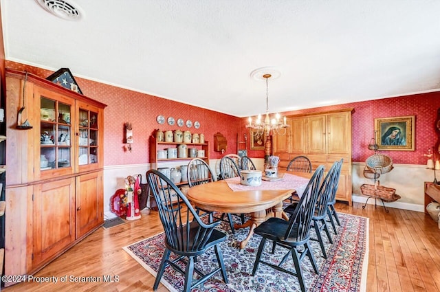 dining area featuring light wood-type flooring, an inviting chandelier, and ornamental molding