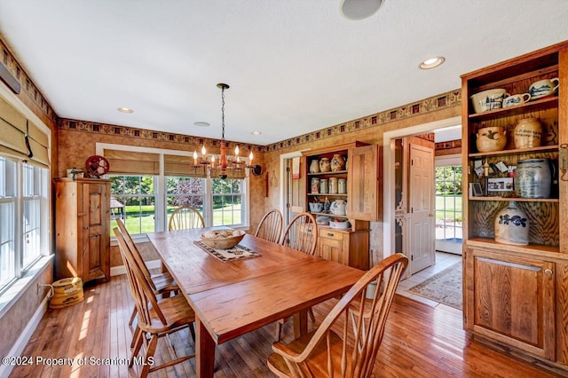 dining area featuring hardwood / wood-style flooring, a wealth of natural light, and a notable chandelier