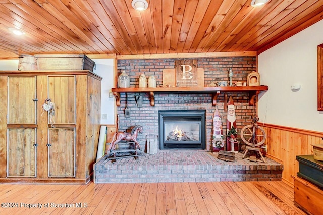 unfurnished living room with a fireplace, light hardwood / wood-style flooring, and wood walls