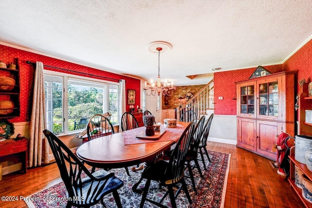 dining room with a chandelier, a textured ceiling, dark wood-type flooring, and ornamental molding