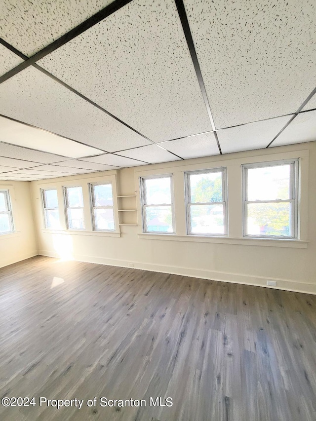 unfurnished room with hardwood / wood-style floors and a drop ceiling