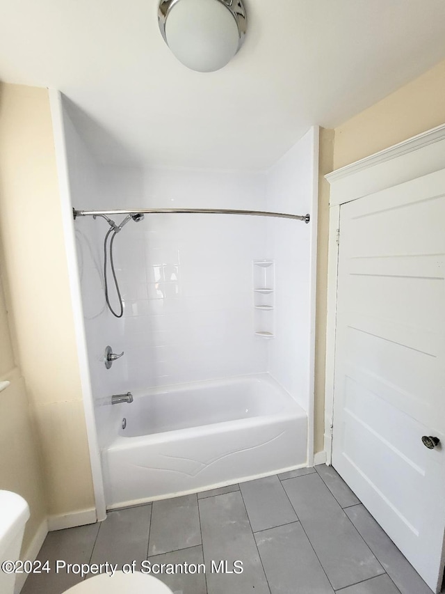 bathroom featuring tile patterned flooring, shower / bathing tub combination, and toilet