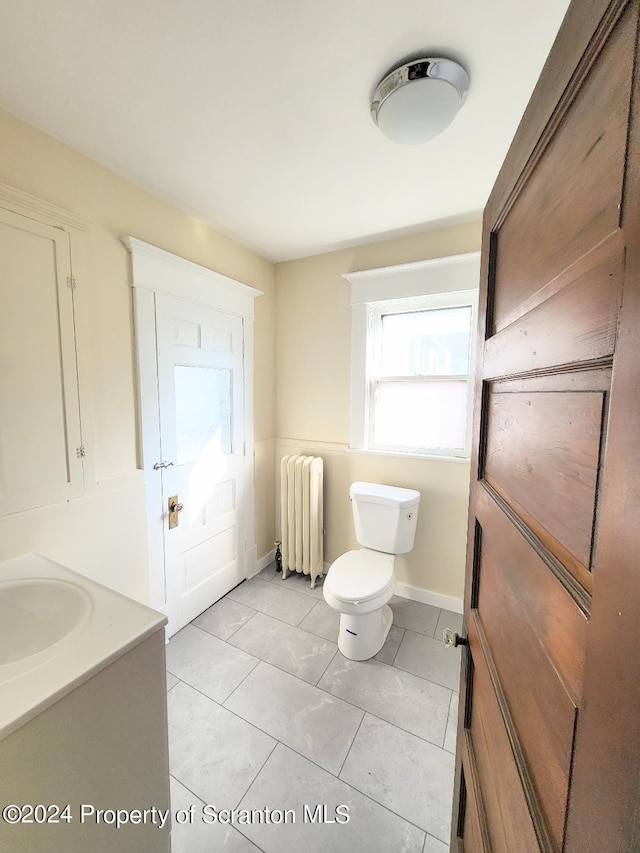 bathroom featuring tile patterned flooring, vanity, toilet, and radiator