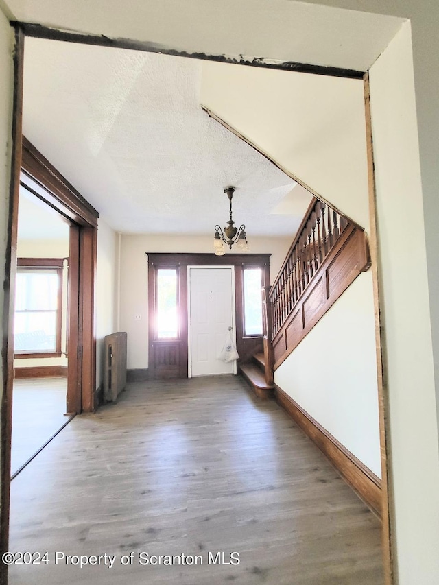 foyer featuring hardwood / wood-style flooring, a textured ceiling, and an inviting chandelier