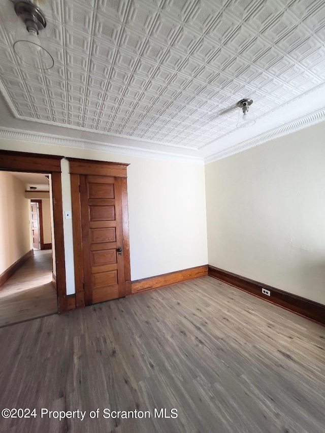 empty room featuring crown molding and wood-type flooring