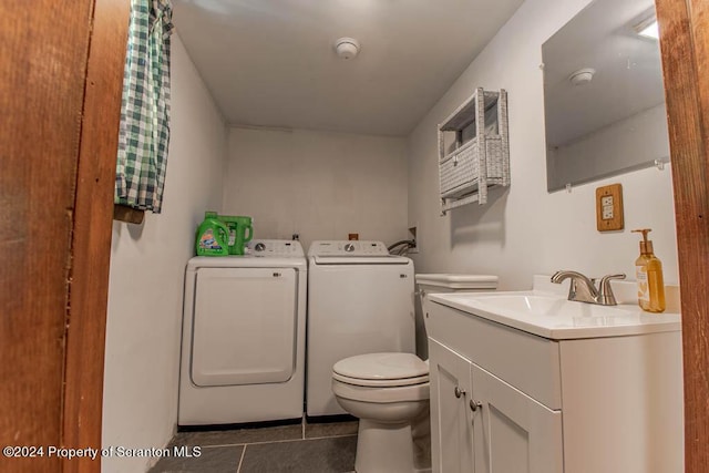 bathroom featuring tile patterned flooring, vanity, washing machine and dryer, and toilet