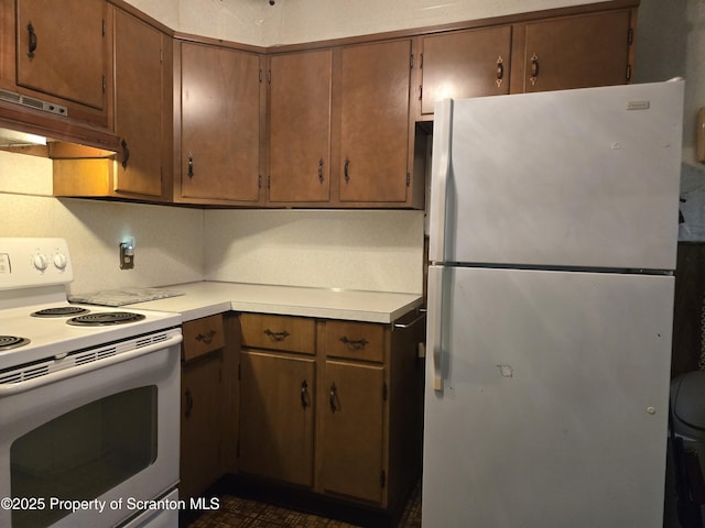 kitchen featuring white appliances, under cabinet range hood, and light countertops