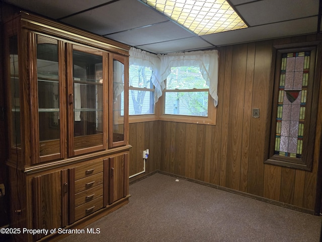 unfurnished room featuring dark colored carpet and wooden walls