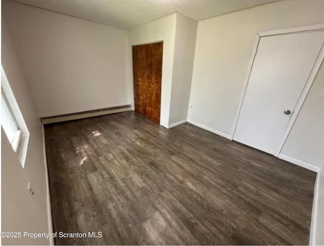 1034 Plane St, Avoca, PA 18641 - unfurnished bedroom featuring baseboards, a baseboard heating unit, a textured ceiling, and dark wood-type flooring