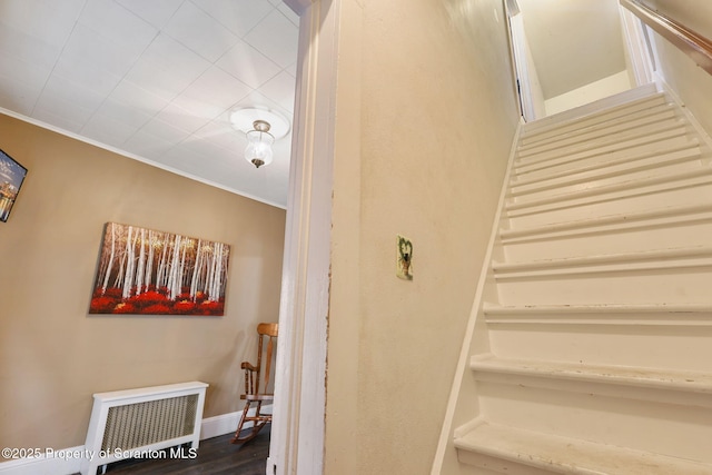 staircase featuring radiator, wood finished floors, and ornamental molding