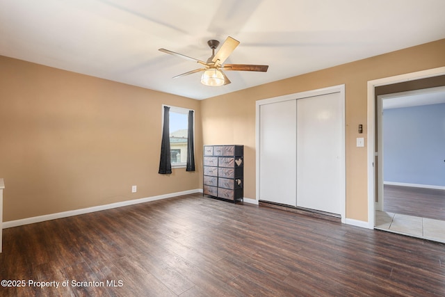 unfurnished bedroom with ceiling fan, baseboards, wood finished floors, and a closet