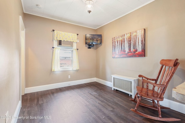 living area with radiator, wood finished floors, baseboards, and ornamental molding