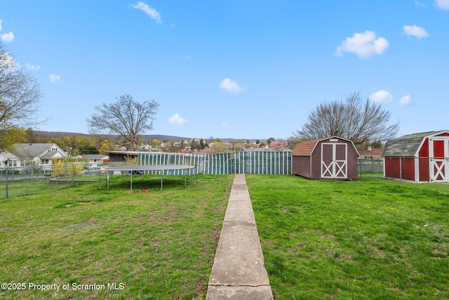 view of yard with a fenced backyard, an outbuilding, a shed, and a trampoline