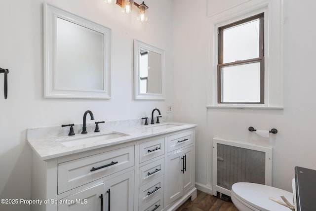bathroom with radiator, double vanity, toilet, and a sink