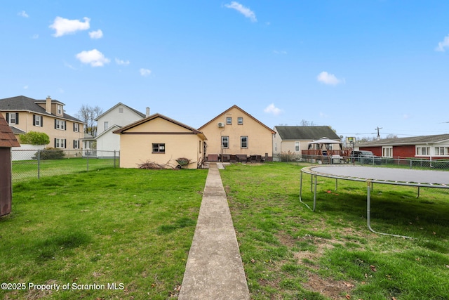 view of front of home featuring a fenced backyard, a front yard, and a trampoline