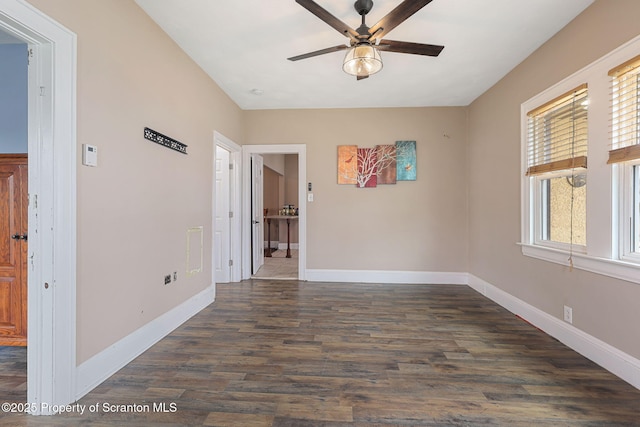 empty room with baseboards, dark wood-style floors, and ceiling fan