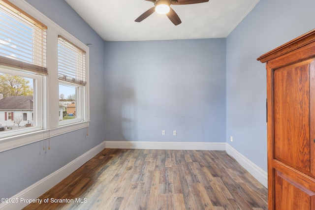empty room with ceiling fan, baseboards, and wood finished floors