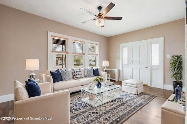 living area with wood finished floors, baseboards, and ceiling fan