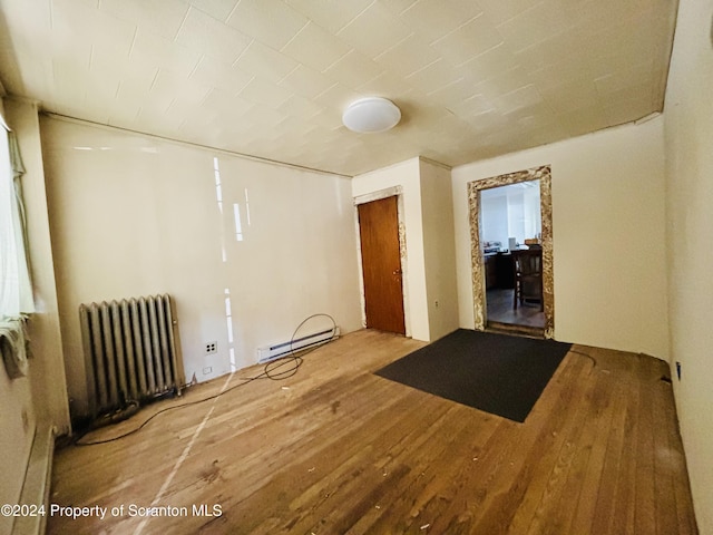 spare room featuring wood-type flooring, a baseboard radiator, and radiator