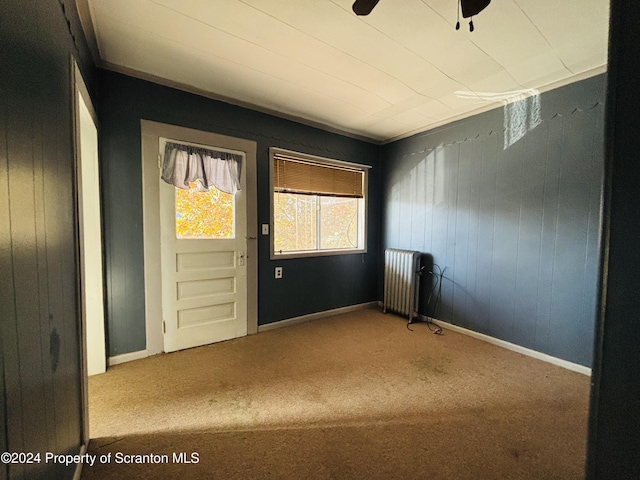 interior space featuring ceiling fan, radiator heating unit, and carpet