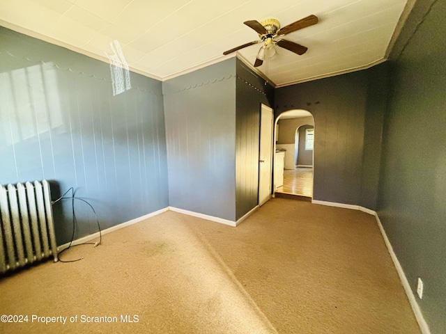 empty room featuring carpet flooring, ceiling fan, ornamental molding, and radiator