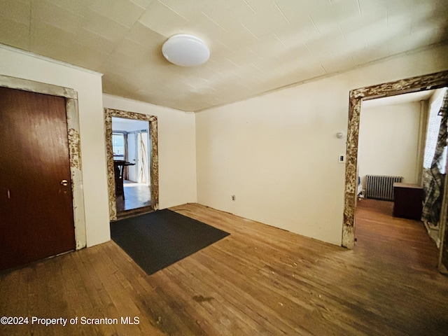 spare room featuring dark hardwood / wood-style flooring and radiator