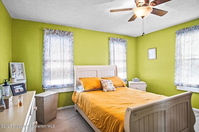 carpeted bedroom with a textured ceiling, baseboards, and a ceiling fan