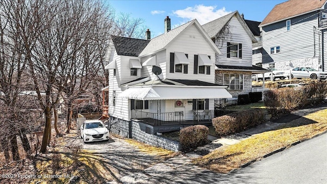 view of front of property featuring covered porch, a chimney, and roof with shingles