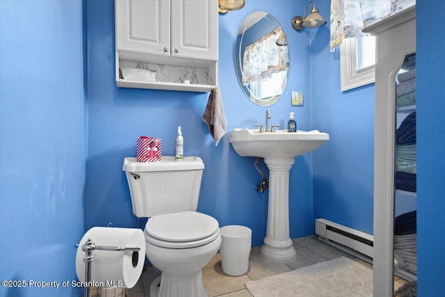 half bathroom featuring tile patterned floors, toilet, and a baseboard radiator