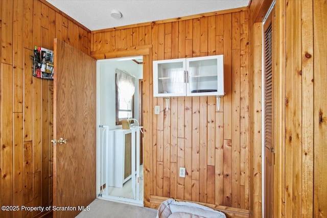 doorway to outside with wooden walls and carpet flooring