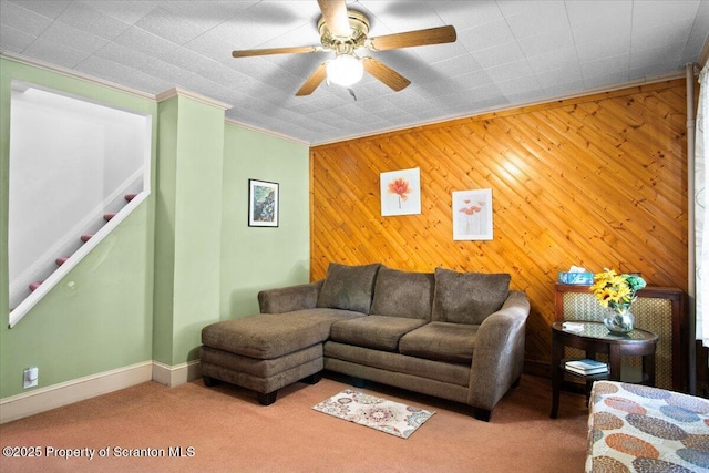 living room featuring baseboards, carpet floors, ceiling fan, stairs, and ornamental molding