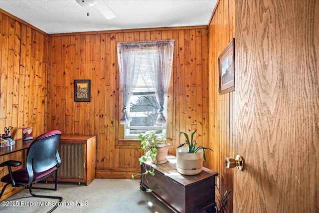 office area featuring a ceiling fan, a textured ceiling, wood walls, and carpet flooring