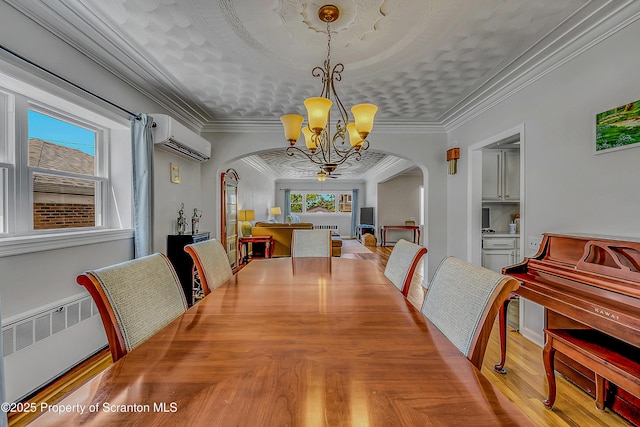 201 Franklin St, Dunmore, PA 18512 - dining area featuring arched walkways, a wall unit AC, a chandelier, radiator heating unit, and plenty of natural light