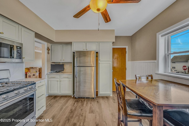 201 Franklin St, Dunmore, PA 18512 - kitchen featuring appliances with stainless steel finishes, ceiling fan, light wood finished floors, a wainscoted wall, and light countertops