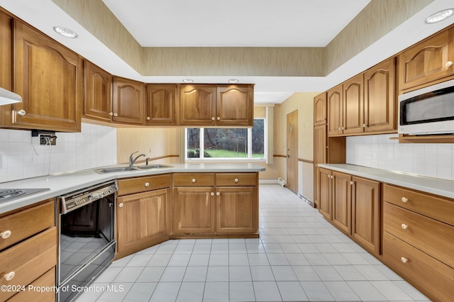 kitchen with dishwasher, backsplash, baseboard heating, and sink