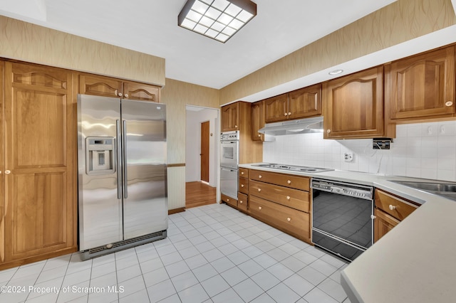 kitchen featuring backsplash, sink, light tile patterned flooring, and white appliances