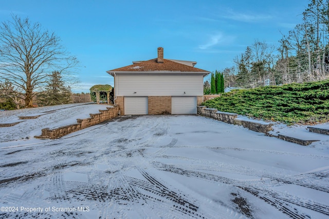 view of snow covered exterior with a garage