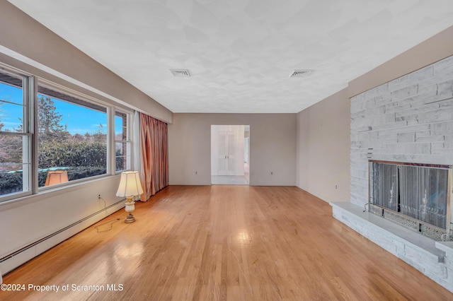 unfurnished living room with baseboard heating and light hardwood / wood-style floors