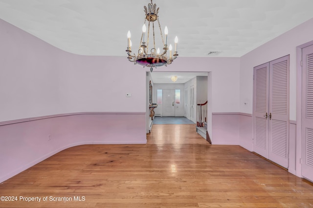 unfurnished dining area featuring light wood-type flooring and a notable chandelier