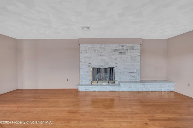 unfurnished living room with light hardwood / wood-style floors and a stone fireplace