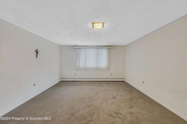 carpeted spare room with a baseboard heating unit