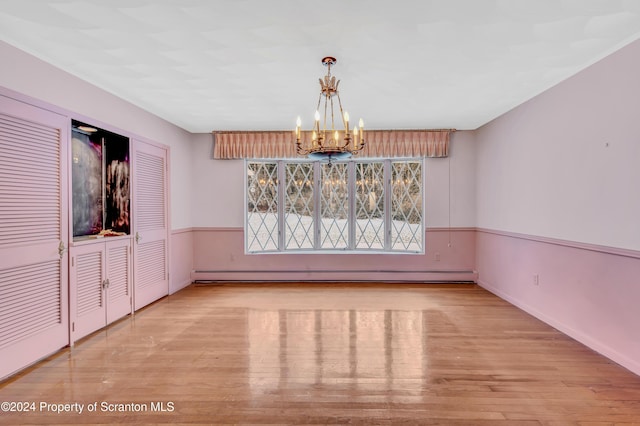 unfurnished dining area with a notable chandelier, light hardwood / wood-style floors, and a baseboard heating unit