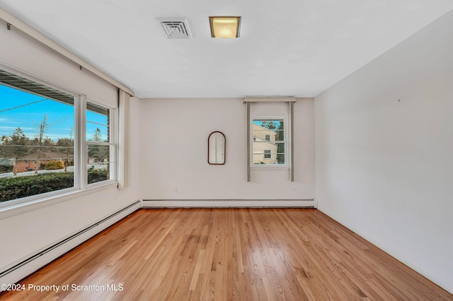 unfurnished room with light hardwood / wood-style flooring and a baseboard heating unit